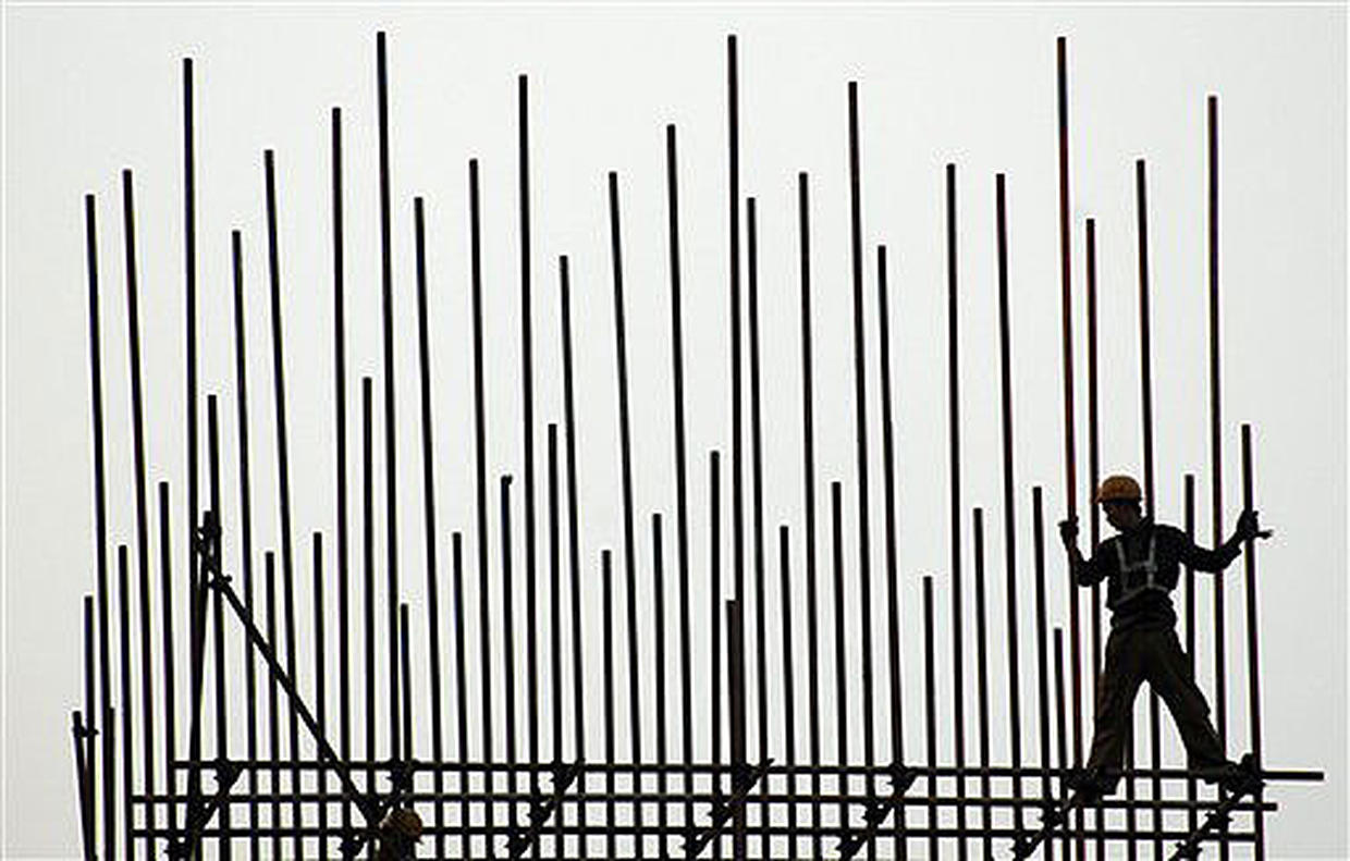 construction worker precariously perched at the edge of a framework of scaffolding