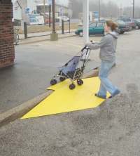 woman pushing stroller up curb cut